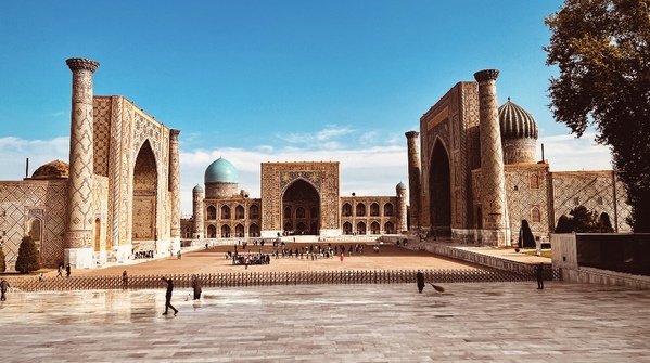 サマルカンドのレギスタン広場の壮大な風景。青い空の下、モスクとマドラサの美しい建築が並ぶ。