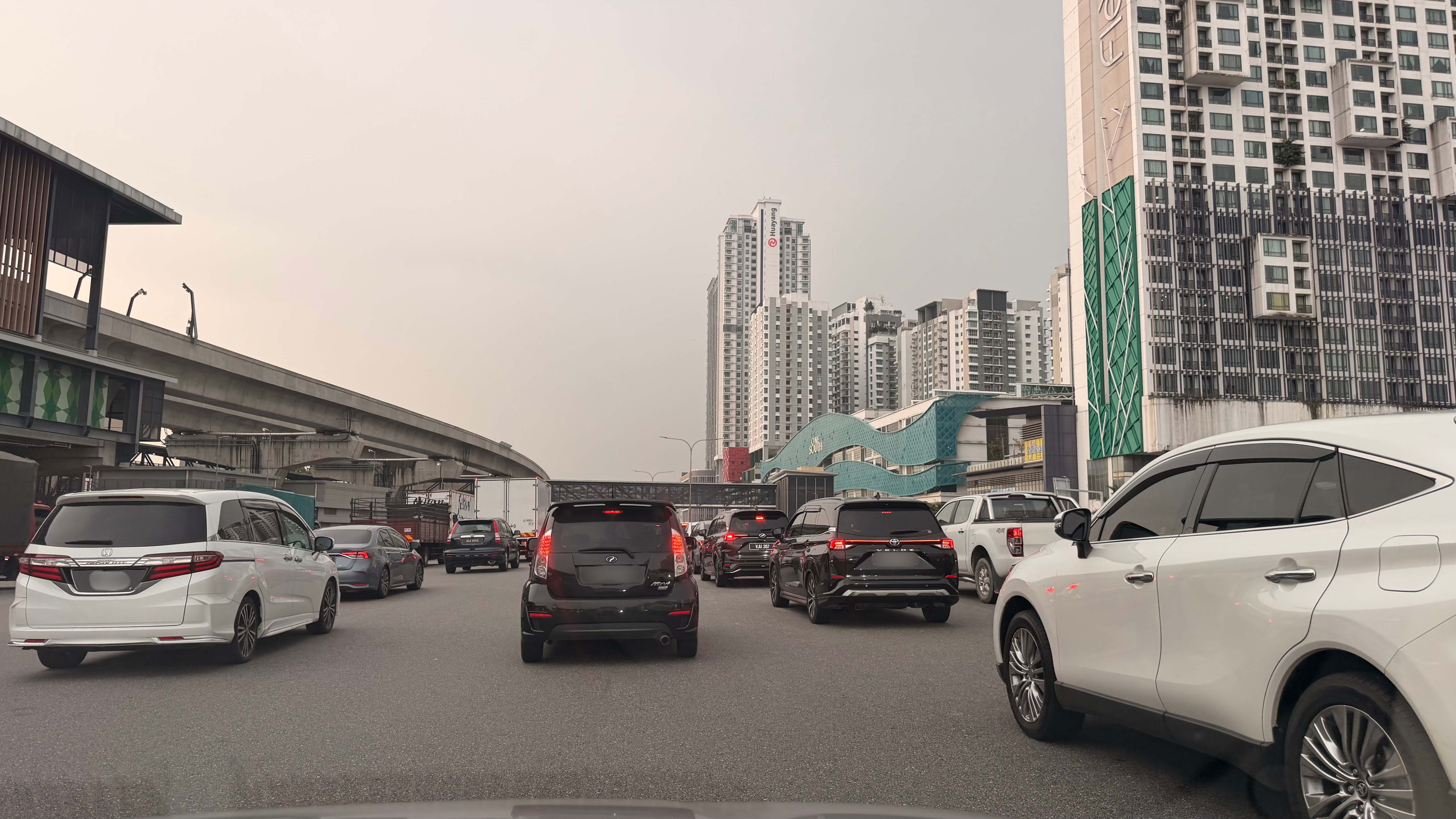 都市の交通渋滞の様子を捉えた写真で、複数の車両が並んでいる。背景には高層ビルや高架道路が見える。